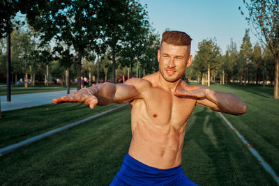 Portrait of young man exercising on field