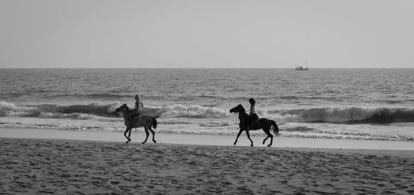 People on beach against clear sky