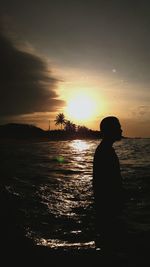 Silhouette man looking at sea against sky during sunset