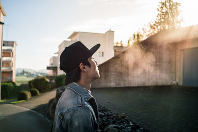 Side view of young man standing in city during sunset