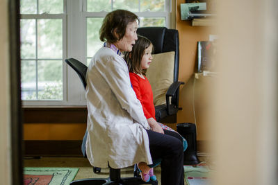 Side-view of grandmother and child sitting close together watching tv