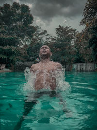 Man swimming in pool against trees