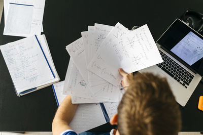 Man holding papers with mathematical equations while sitting at table