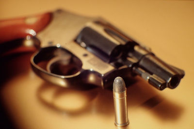 Close-up of bullet and handgun on table