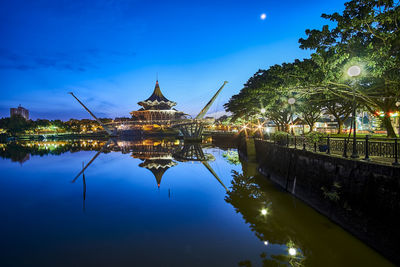 Reflection of illuminated buildings in lake against blue sky