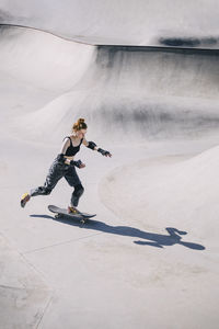 Girl with skateboard skating on sunny day