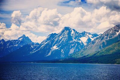 Scenic view of snow covered mountains against cloudy sky