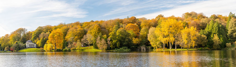 Panoramic photo of the autumn colours around the lake at stourhead gardens in wiltshire.