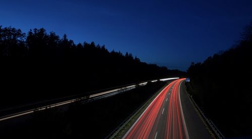 Light trails on highway against sky at night