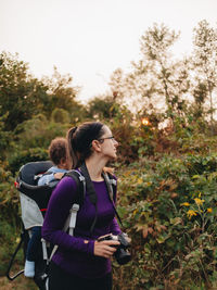 Young woman looking at camera while standing by plants