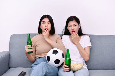 Friends having food and drink while watching tv at home