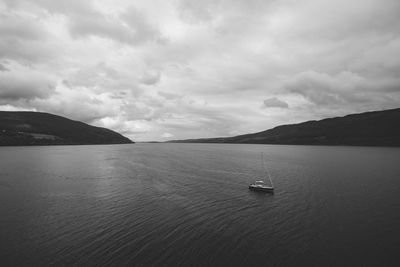 Boats sailing in sea against cloudy sky