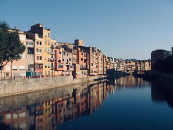 Buildings by river against sky in city