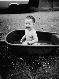 Cute baby girl sitting in bathtub at back yard