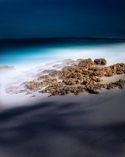 Scenic view of rocks on beach against sky