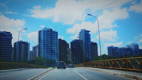 Road in city against cloudy sky