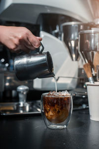 Cropped hand pouring coffee in glass