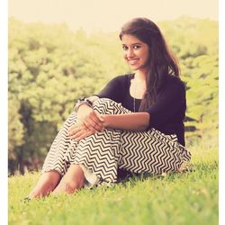 Portrait of young woman sitting on field