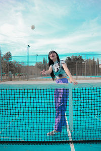 Full length portrait of woman standing in tennis courts