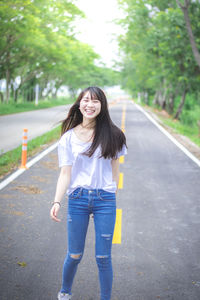 Full length of smiling young woman standing on road