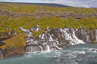 Dramatic hraunfossar falls streaming out of lava field near husafell, iceland