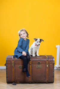 Girl 5 years old with a dog sit on a chest.