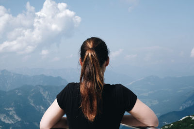 Rear view of woman standing against mountains and sky