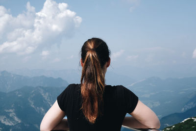 Rear view of woman looking at mountains against sky