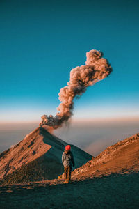 Man standing on mountain road against clear blue sky