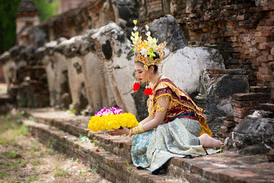 Woman in traditional clothing standing against wall