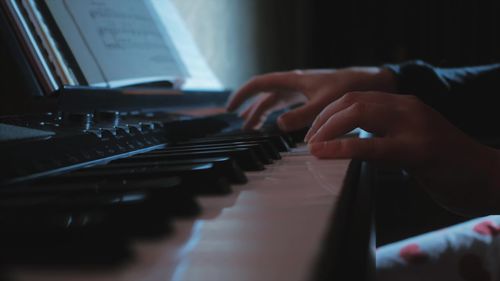 Cropped hands of woman playing piano