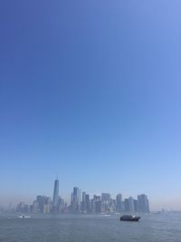 Sea by buildings against clear sky