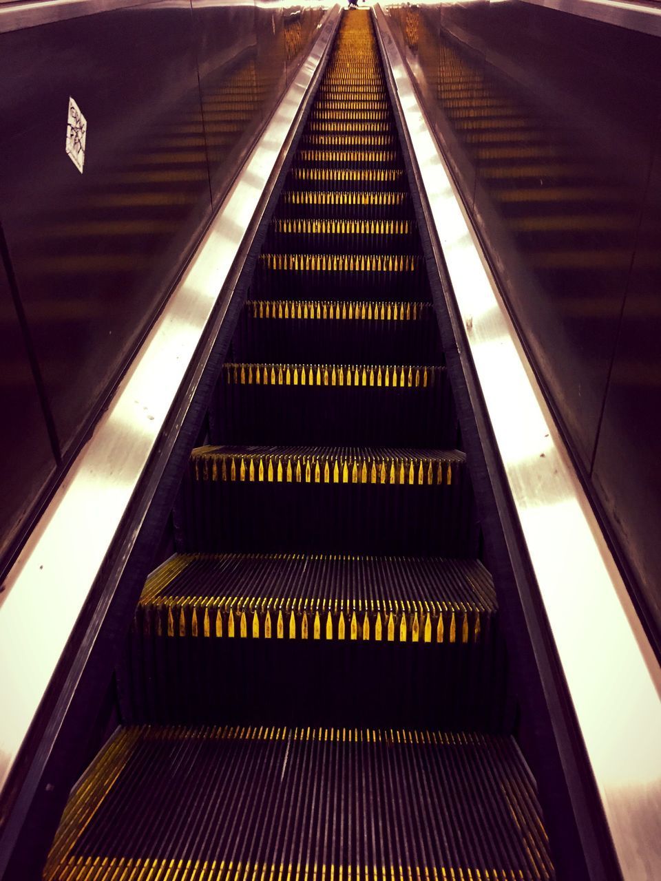 LOW ANGLE VIEW OF ESCALATOR IN ILLUMINATED STAIRCASE