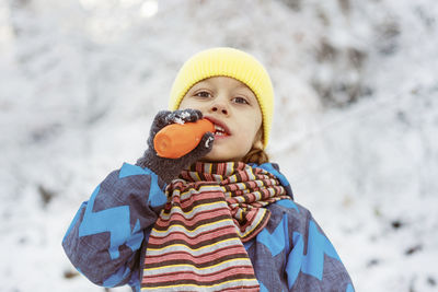 Portrait of cute boy eating carrot during winter