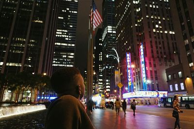 Man looking at illuminated buildings in city