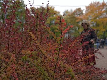 Smiling woman standing by plants during autumn