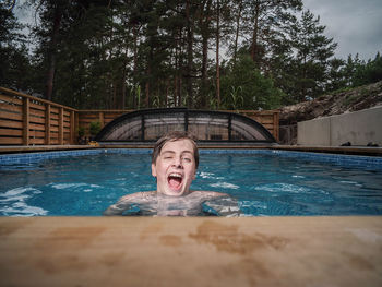 Boy in swimming pool against trees