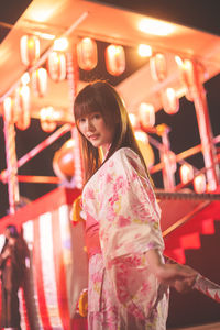 Portrait of woman standing in illuminated city during event