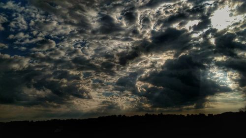 Low angle view of dramatic sky over silhouette landscape