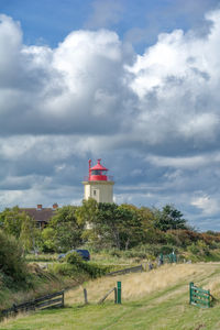 Lighthouse on field against sky