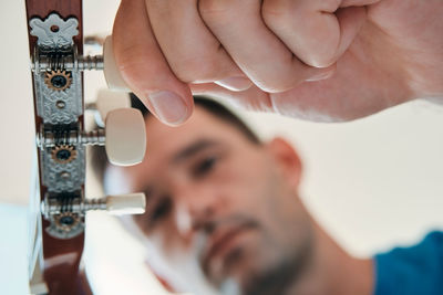 Low angle view of man holding guitar sitting at home