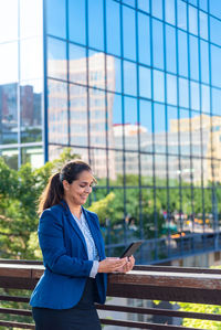 Woman standing by modern building in city