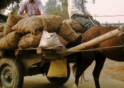 Horses pulling wagon with sacks of goods and people