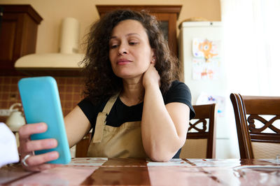 Portrait of young woman using mobile phone at table