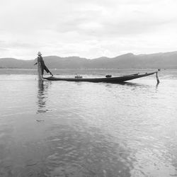 Man in boat on shore against sky