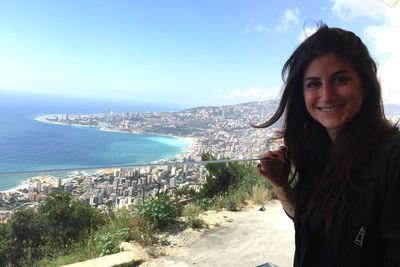 Portrait of smiling woman with coastline in background