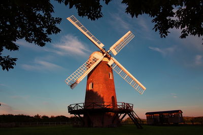 Low angle view of traditional windmill on field against sky