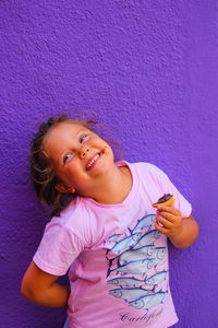 Portrait of happy girl holding pink against wall