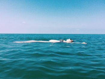 Pregnant woman swimming in sea against clear sky