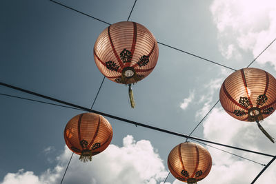 Low angle view of chinese lanterns hanging on cable against sky